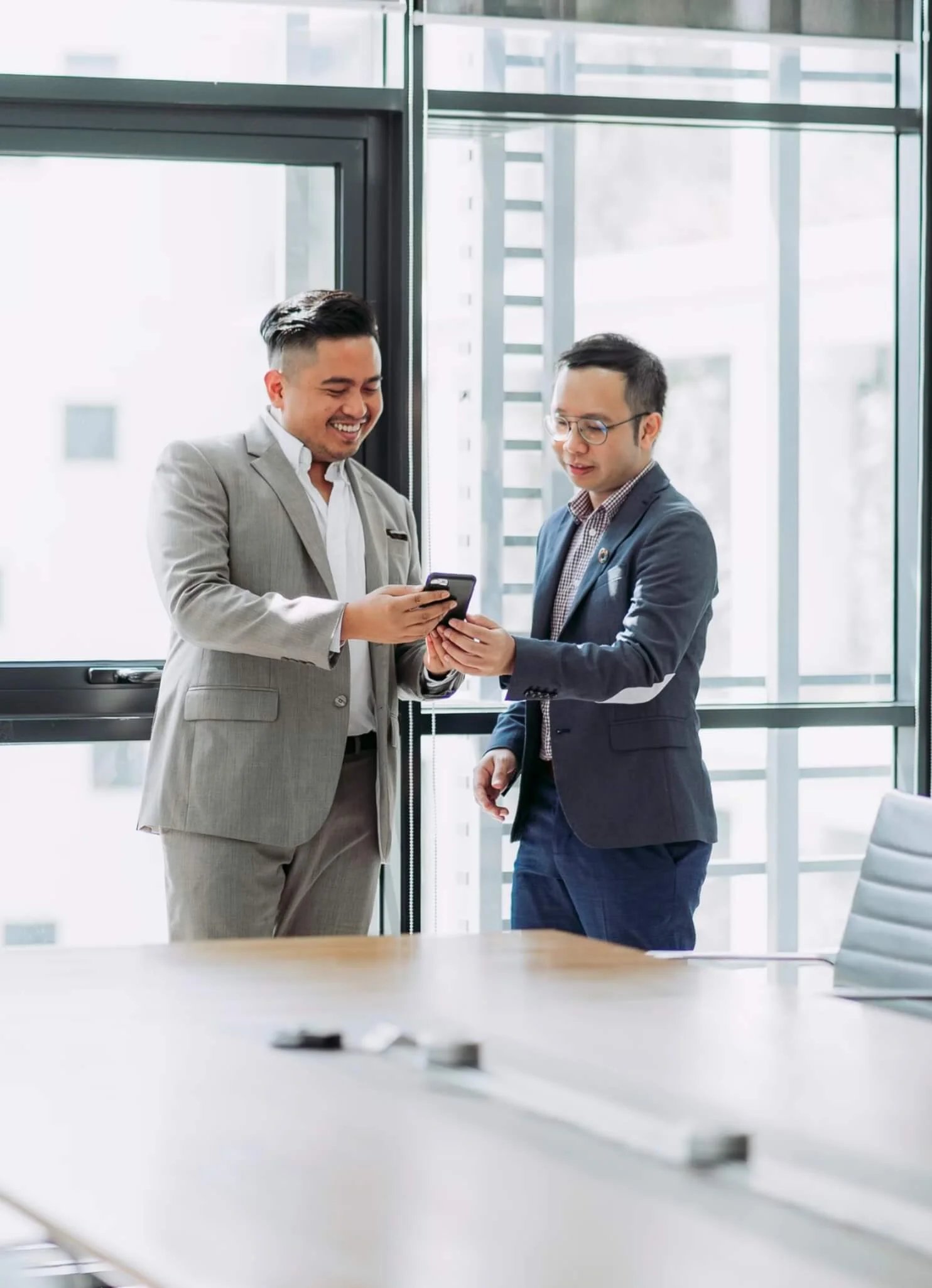 Two professionals in business attire having a friendly conversation in a modern office setting